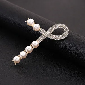 Macro di una elegante clip per capelli con perle bianche e strass su base metallica dorata