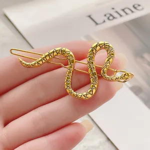 Detalle de una pinza para el cabello de serpiente dorada con textura de escamas y aleación