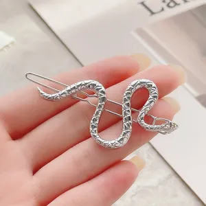 Primer plano de pasador de pelo de serpiente plateado con textura de escamas metálicas