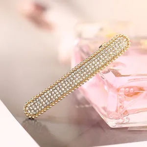 Primo piano del fermaglio dorato con strass bianchi scintillanti e bordi con perline