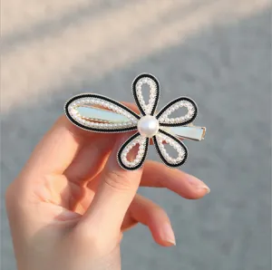 Dettaglio del fermaglio per capelli a fiore con perle bianche e bordi di perline nere