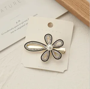 Dettaglio della molletta a fiore con petali in smalto nero, strass e perla centrale