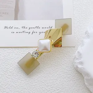 Detailed close-up of geometric gold hair clip with opal stone and faux pearl detail
