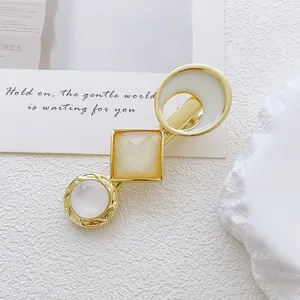 Detail of a geometric hair clip with opal stones and gold alloy on a minimalist base