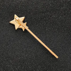 Barrette cheveux en métal doré avec double étoile et finition mate sur fond noir