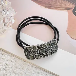 Close-up of black triple-strand hair tie with dark grey rhinestone metal accessory