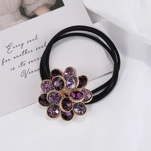 Detalle de una goma de pelo con flor de cristal púrpura y triple banda elástica