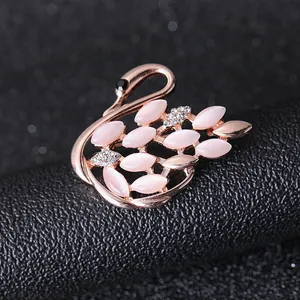 Close-up of rose gold swan brooch with pink cat eye stone and sparkling crystals