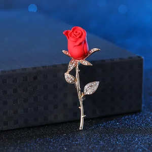 Detail of elegant red rose brooch with gold stem and micro-pave crystals on dark background
