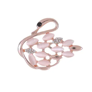 Detailed close-up of a rose gold swan brooch with pink marquise stones and sparkling rhinestones