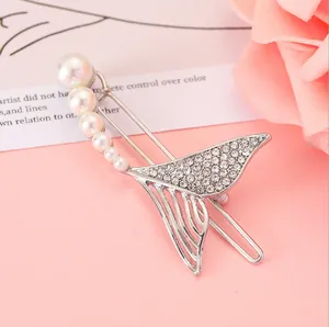 Dettaglio di fermaglio per capelli a sirena con perle e strass su sfondo rosa