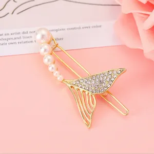 Dettaglio macro della clip per capelli a coda di pesce dorata con perle e strass lucidi