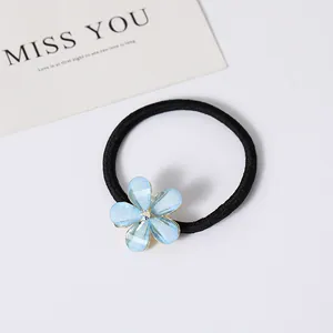 Détail d'un élastique à cheveux noir avec un pendentif fleur en cristal bleu et strass