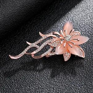 Close-up of elegant rose gold floral brooch with pink petals and sparkling white rhinestones