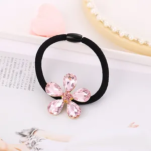 Detalle del coletero con flor de cristal rosa, base dorada y elástico negro