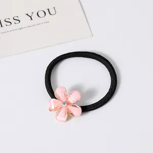 Détail d'un élastique à cheveux avec une fleur délicate en résine rose et strass central