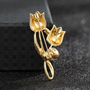 Macro view of gold tulip brooch with white pearl and sparkling zircon detailing