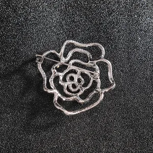 Élégante broche rose argentée avec strass montrant la structure de l'épingle au dos