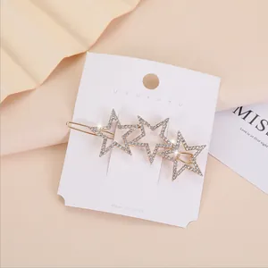 Dettaglio ravvicinato di una clip per capelli a stella dorata con strass su cartoncino