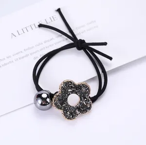 Detalle de coletero negro con dije de flor de cristal gris y cuenta metálica brillante