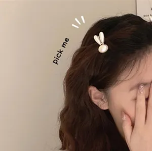 Detailweergave van een schattige crème-witte konijn parel haarclip op golvend bruin haar