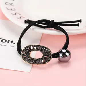 Detalle de goma de pelo negra con anillo de cristal gris oscuro y colgante de bola