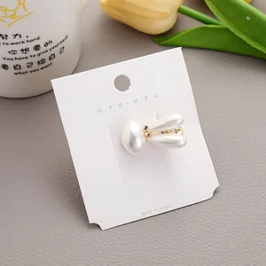 Zoete parelmoer konijn haarclip met gouden metalen accenten op displaykaartje