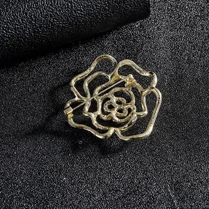 Détail macro d'une broche rose dorée aux lignes évidées sur tissu noir texturé