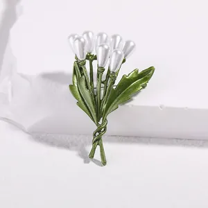 Detail shot of lily of the valley brooch with green leaves and white pearls on stone
