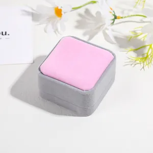 Detail view of a velvet jewelry gift box in grey and pink with daisy props
