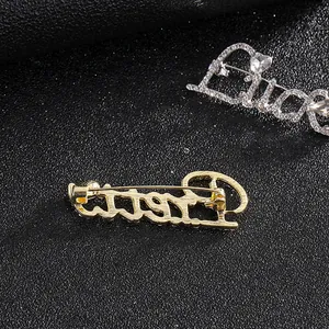 Lucky letter brooch with gold and silver rhinestones on a textured black background