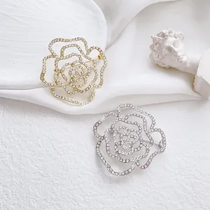 Détails d'élégantes broches roses creuses en or et argent avec des strass blancs