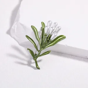 Detailed view of green enamel leaves and drop pearl accents on a botanical brooch