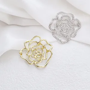 Vue détaillée de broches camélia en métal ajouré doré et strass en cristal argenté