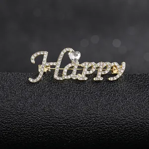 Macro detail of 'Happy' gold brooch with sparkling crystals and heart-shaped rhinestone