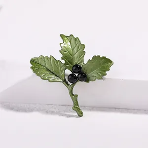 Detail of green leaf enamel brooch with black pearls on a white stone base
