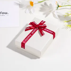 Detailed top view of off-white velvet jewelry box with red ribbon and bow decoration
