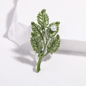 Macro detail of olive green leaf brooch with white pearl on matte stone pedestal