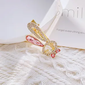 Golden rabbit ear hair clip with white crystals and pink heart stones on knit background