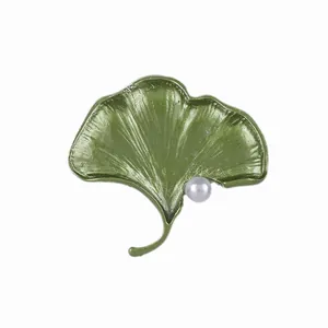 Elegant green ginkgo leaf brooch with white pearl accent on white background