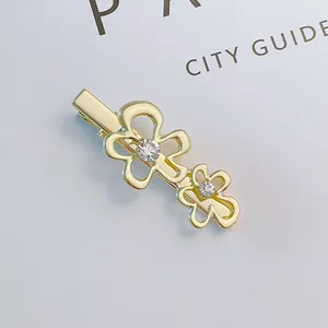 Detail of gold metal flower hair clip with sparkling rhinestones on a white background