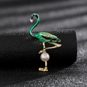 Detalle macro de broche de flamenco con esmalte verde, baño de oro y perla fina