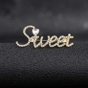 Detail shot of a gold-plated Sweet letter brooch encrusted with sparkling rhinestones