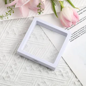 Close-up of white 3D floating jewelry display box with clear PE film on textured background
