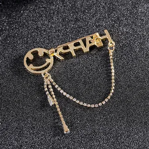 Golden Happy letter brooch with rhinestone tassels and smiley face on black background