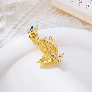 Élégante broche dauphin en métal doré sur plateau blanc avec fond en tricot