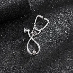 Detalle de un broche de estetoscopio plateado sobre un fondo negro con textura brillante
