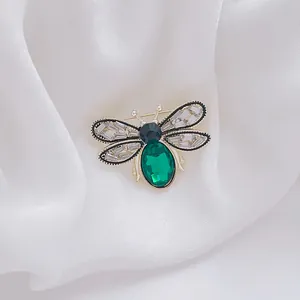 Detail of bee brooch with emerald gemstone, crystal wings and gold metal plating