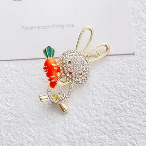 Macro detail of cute rabbit brooch with rhinestones holding an orange enamel carrot