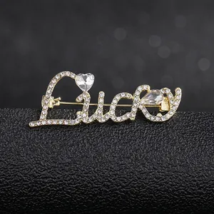Macro detail of Lucky brooch in gold alloy with white rhinestones on black stand